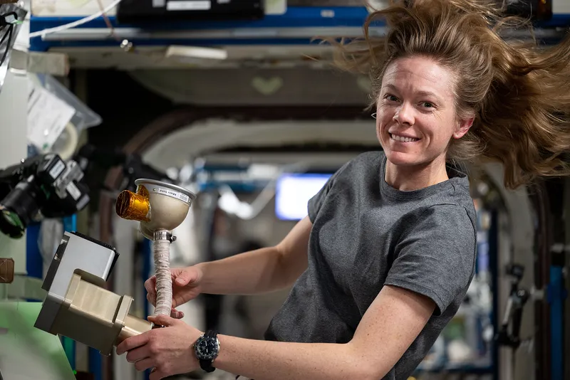 An astronaut cleaning and servicing life support components on the International Space Station.