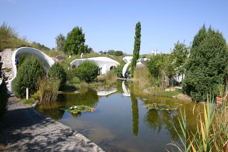 Earth houses in Switzerland, built into grassy mounds around a pond.