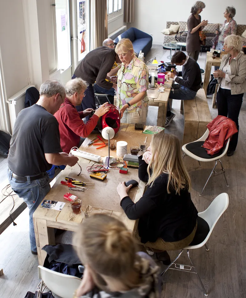 Volunteers help people mend their belongings at a Repair Café in the Netherlands.