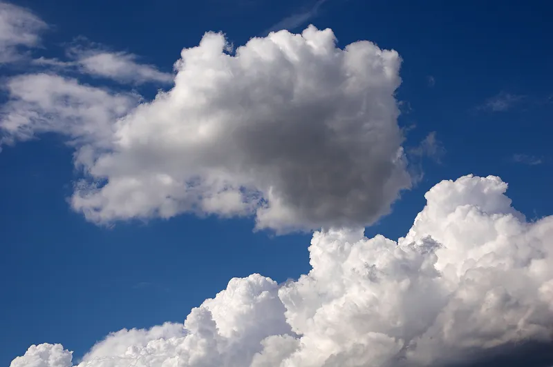Puffy cumulus clouds in a blue sky.